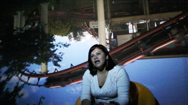 Woman speaking in front of an upside down image of an amusement park
